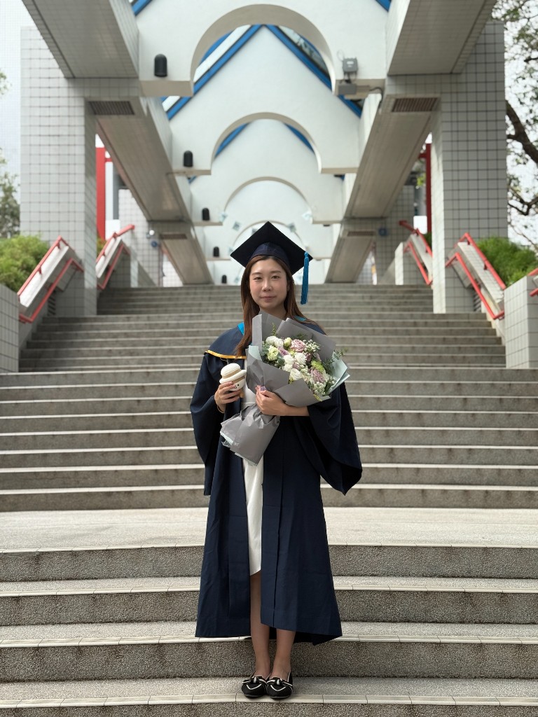 Janice Lee in graduation regalia, smiling with a bouquet of flowers